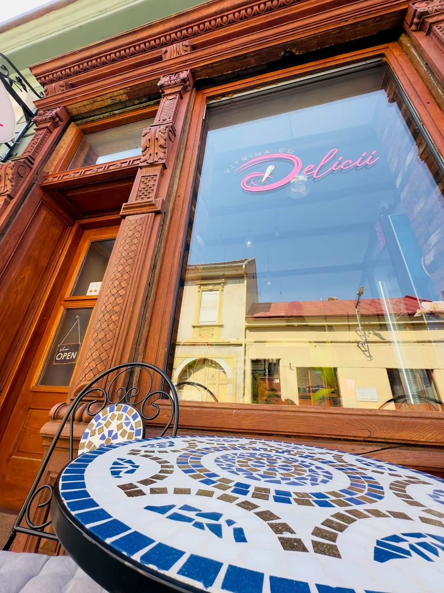 Vitrina cu logo-ul Vitrina cu Delicii, în rama de lemn sculptat, cu o masă cu mozaic în față